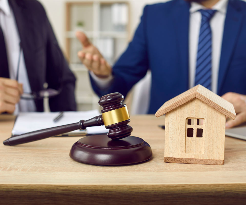 Image showing a close up of two people sat at a desk with a gavel and a model of a house