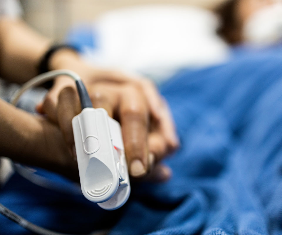 Image showing a close up of someone holding the hands of someone in a hospital bed with a pulse monitor on their finger