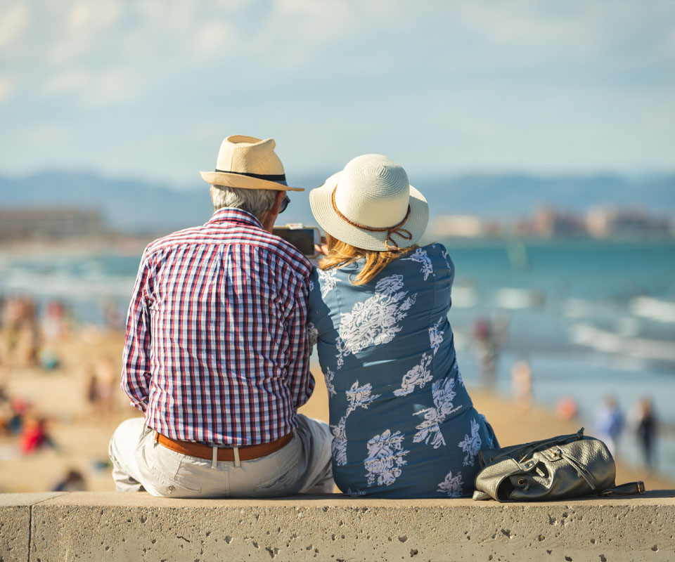 Image showing an older couple sitting on a wall looking out at the beach