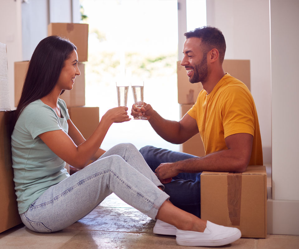 Image showing a happy couple sitting on the floor next to some cardboard boxes toasting with glasses