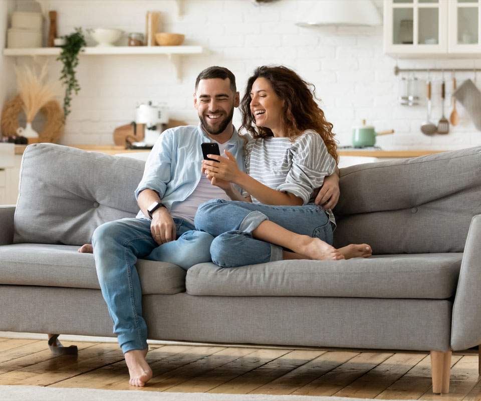 Image showing a happy couple sitting on a sofa looking at a mobile phone