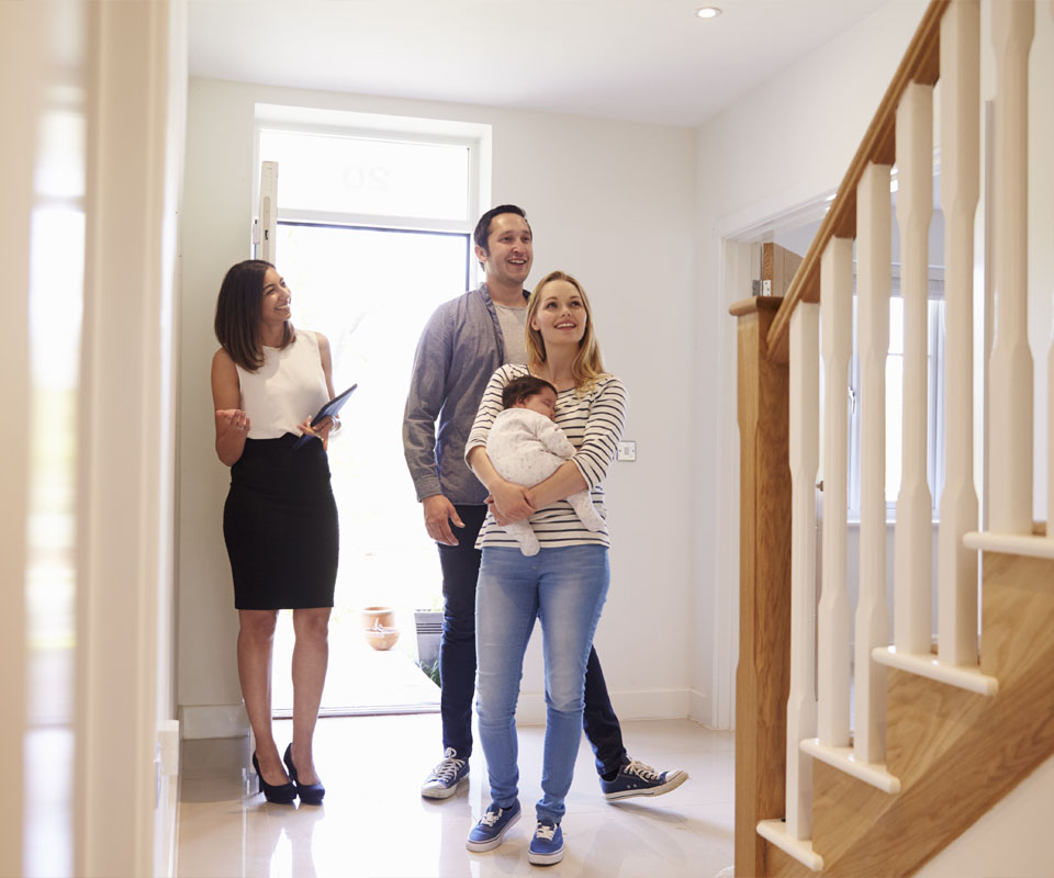 Image showing an estate agent showing a house to a couple and their baby