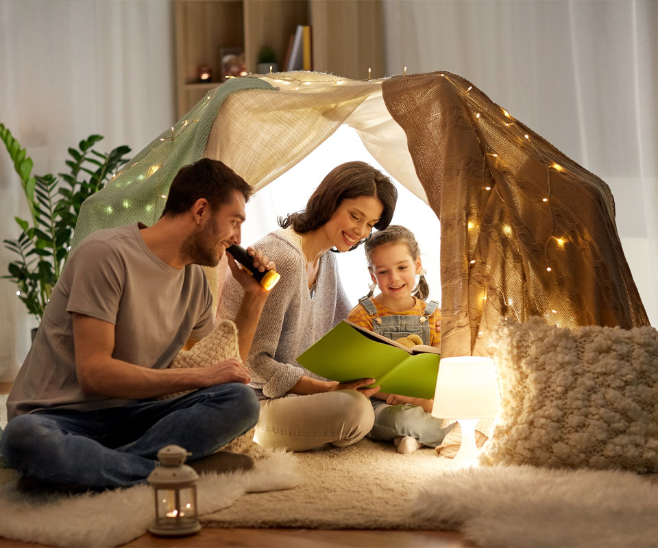 Image showing a family inside a homemade fort reading a book together