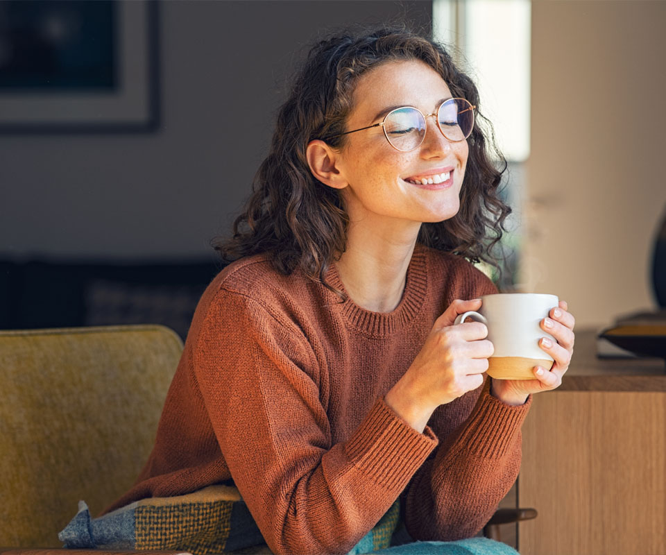 Image showing a smiling woman sitting on the sofa with a mug