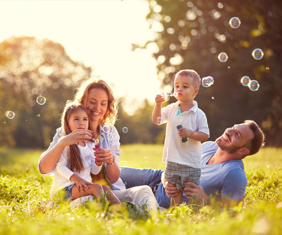 Image showing a happy family blowing bubbles outside