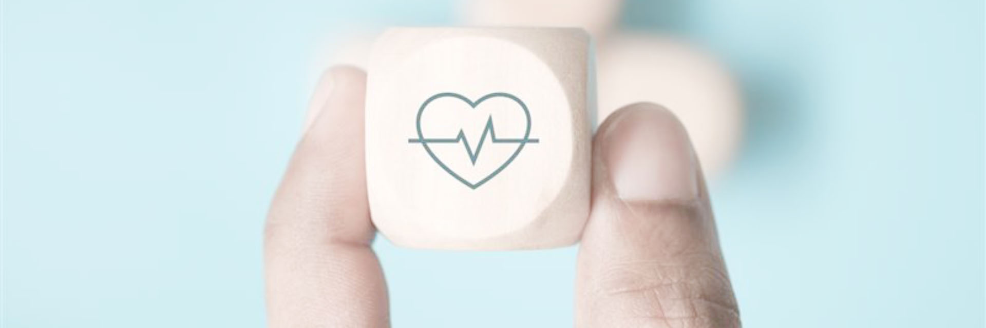 Photo of a finger and thumb holding up a wooden die with a heart rate symbol on it