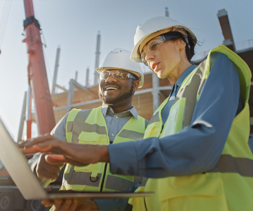 Image showing two people in high vis vests and hard hats going over some plans on a building site
