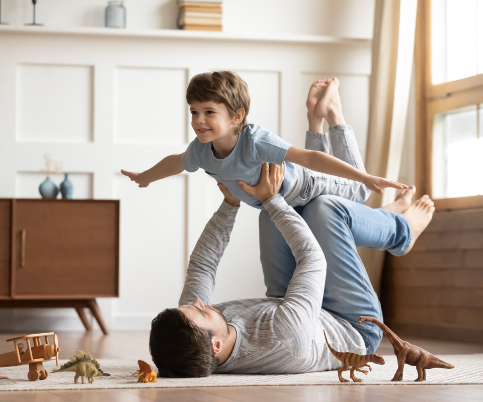 Image showing a Dad holding his son up whilst lying on the floor