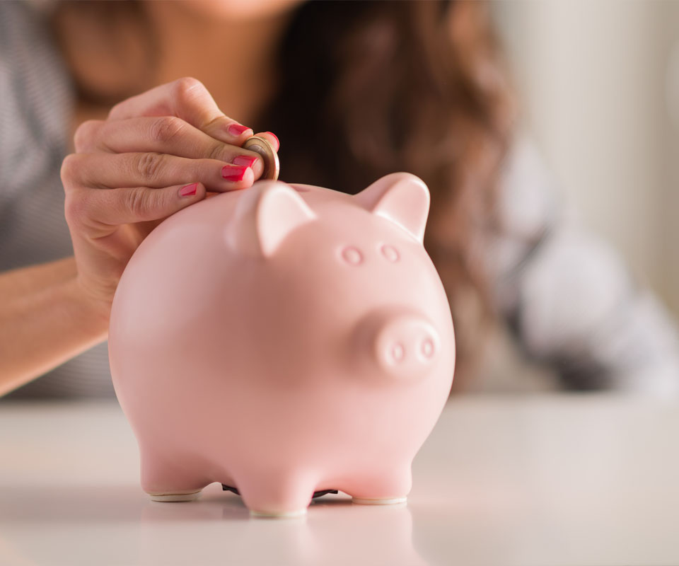 Image showing a close up of a woman putting a coin in a piggy bank 