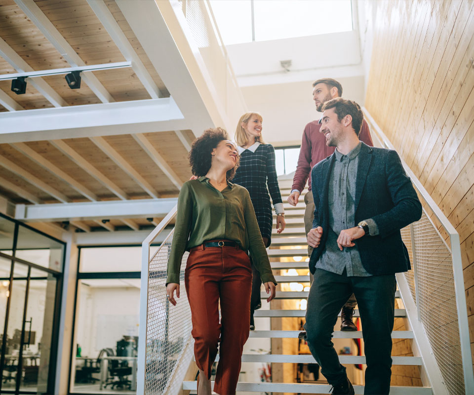 Image showing a group of colleagues walking down stairs chatting in an open plan office environment