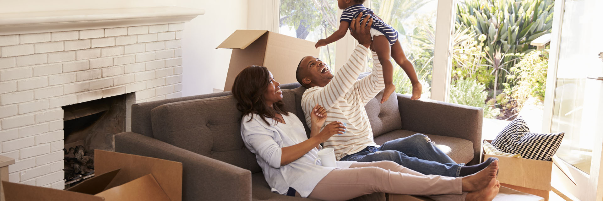 Image showing a couple and their toddler relaxing on the sofa surrounded by boxes