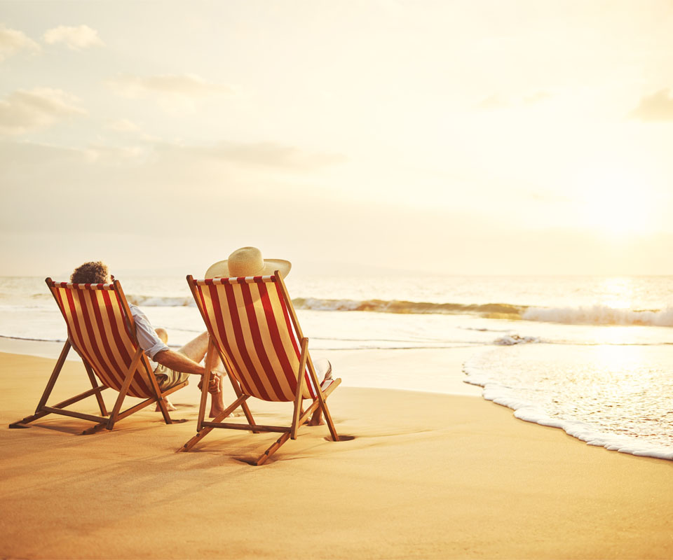 Image showing an older couple relaxing on some deckchairs, looking out at the sea