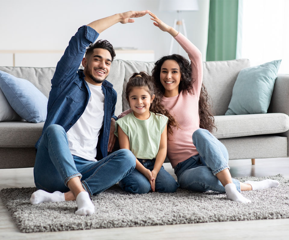 Image showing a family of three sitting on the floor holding their hands above their heads to make a roof