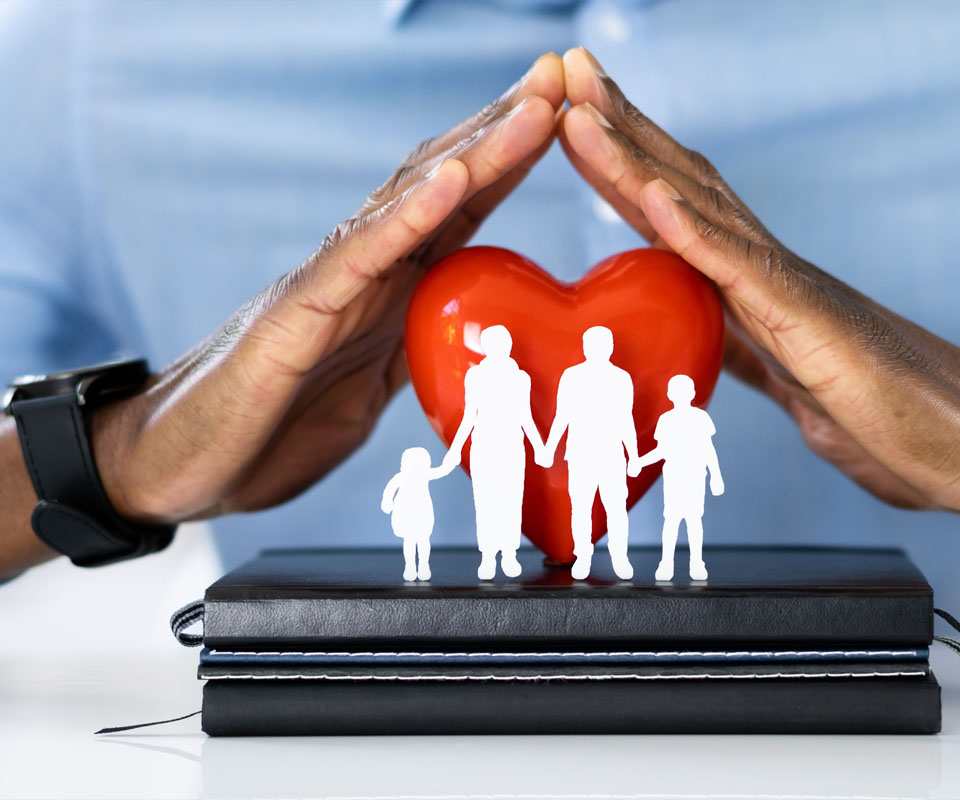 Image showing a close up of a business man holding his hands over a model of a heart and a family