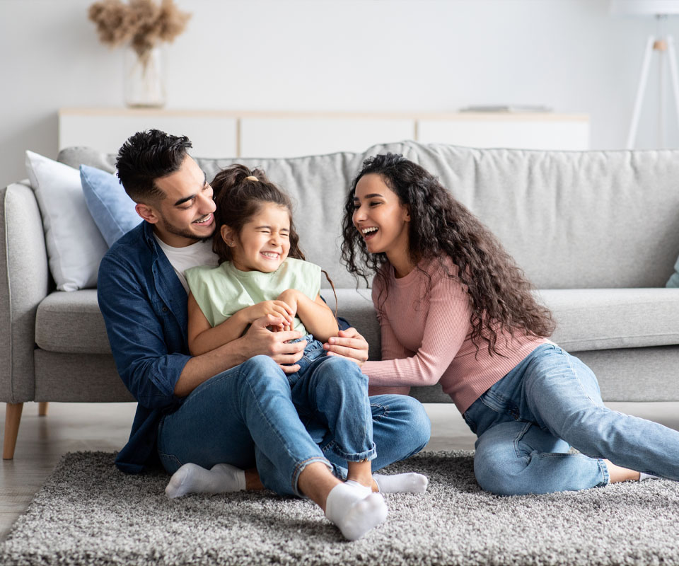 Image showing a happy family with their daughter sat on the floor in front of a sofa