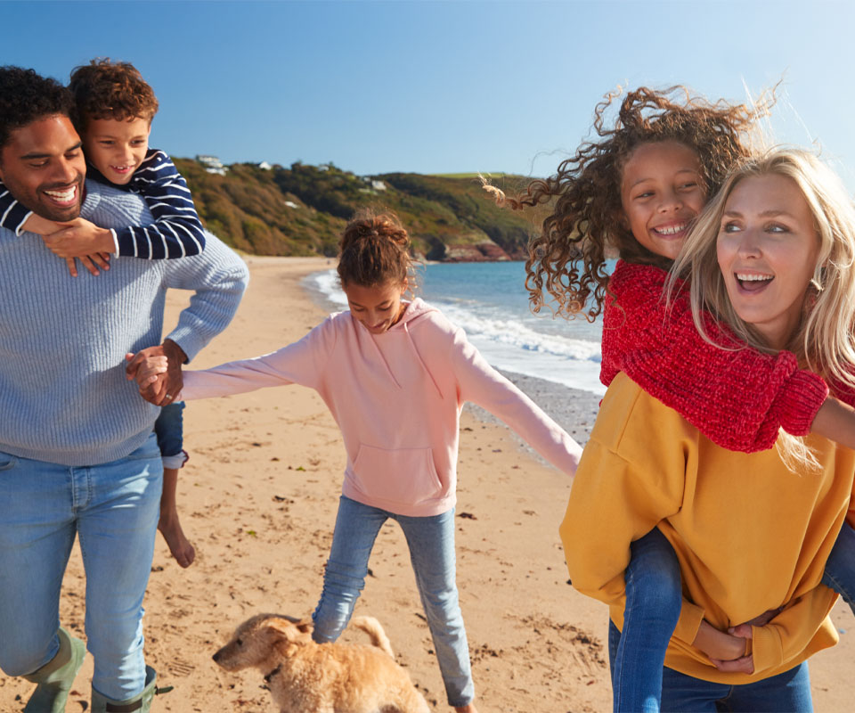 Image showing a happy family of five walking on the beach with their dog 