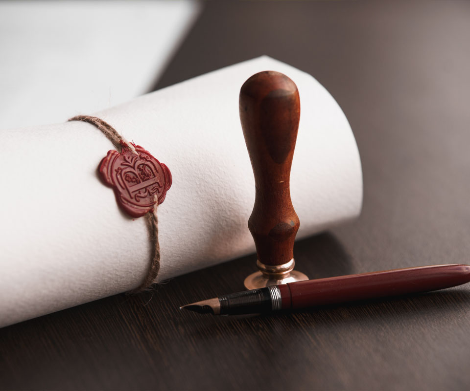 Image showing a document wrapped in a scroll next to a wax seal and a fountain pen